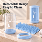 A pet grooming brush holder set with a clear cylindrical cup, a ribbed light blue lid, a blue silicone scrubber mat, and a blue ring, displayed on a beige countertop with promotional text reading 'Detachable Design Easy to Clean'.