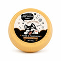 A round yellow plastic container of Jupiter Lee London Pawbalm Nose & Pawbalm Moisturizing Care, featuring a white, black, and brown cartoon label with a husky illustration.