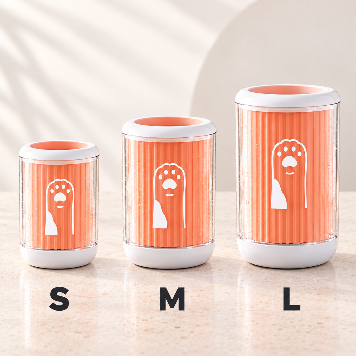 Three pet poop bags in sizes S, M, and L lined up on a light beige countertop. The bags have a ribbed orange design with a white dog silhouette and paw print, clear sides, and white lids and bases.